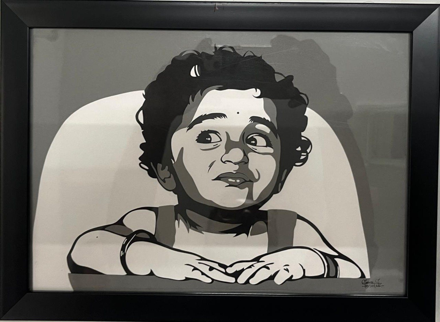 Framed paper-cut portrait of a curly-haired child looking upward