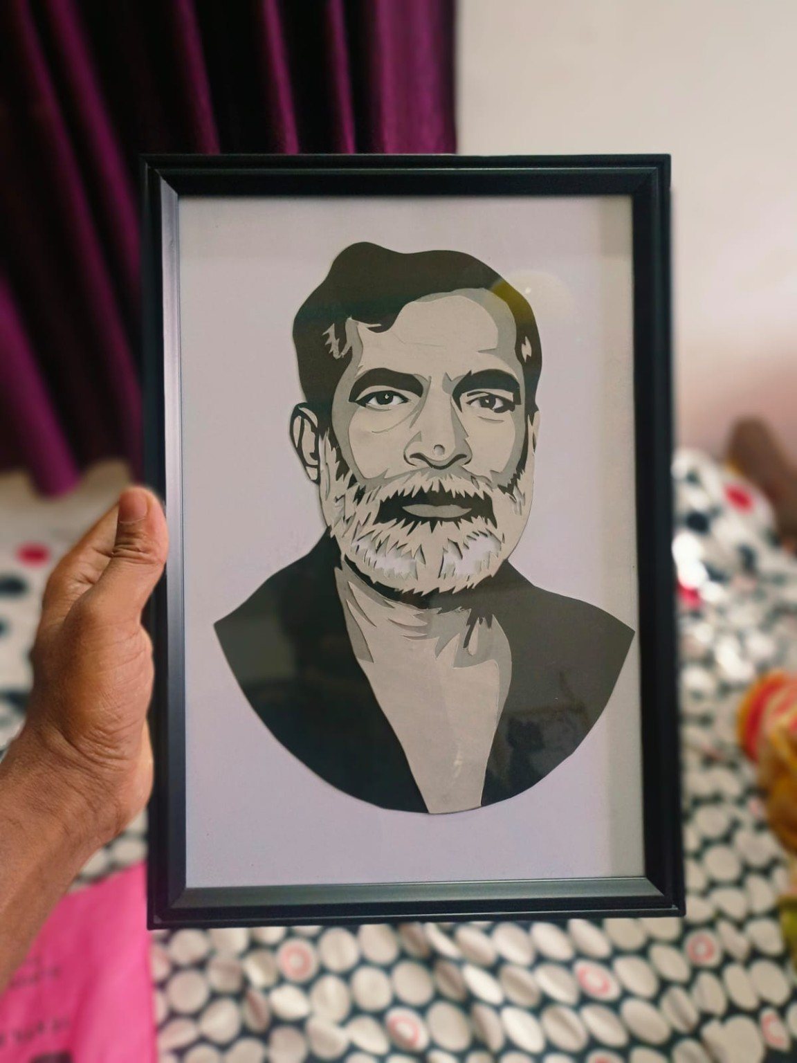 Paper-cut portrait of a man with a graying beard held up in hand