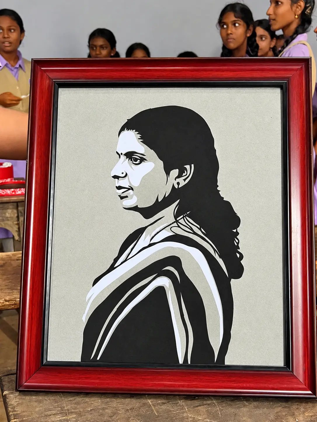 Framed paper-cut profile portrait of a woman in a saree