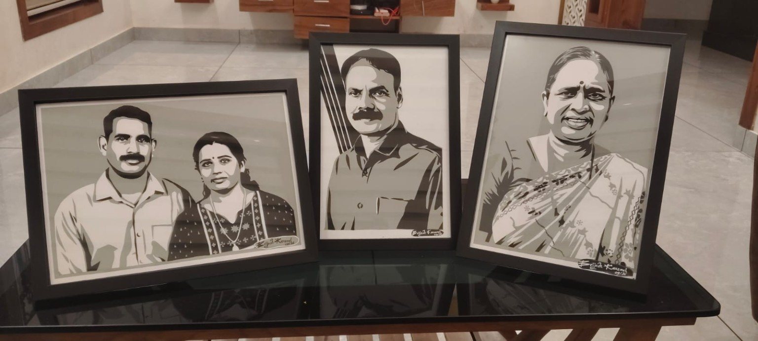 Three framed paper-cut portraits displayed together on a glass table