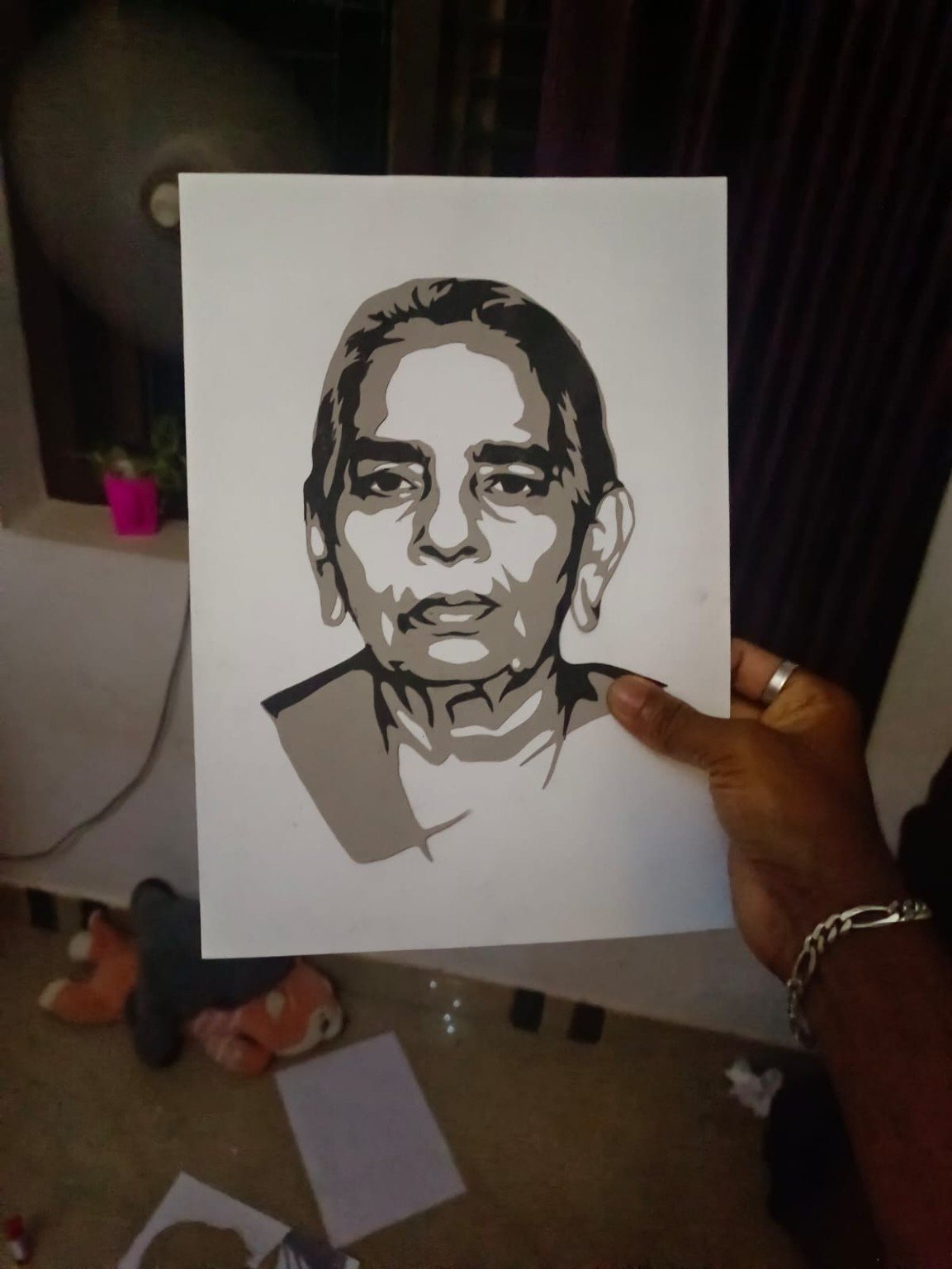 Paper-cut portrait of an elderly woman held up in hand